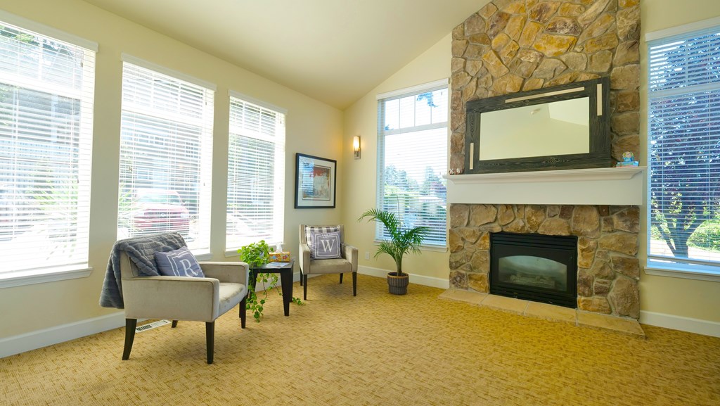 A living room with a stone fireplace and a flat screen TV mounted above it.