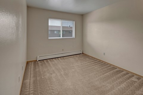 the bedroom of an apartment with a carpet and a window