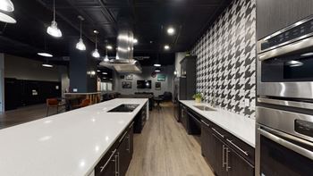 a kitchen with white countertops and black and white tiles on the wall