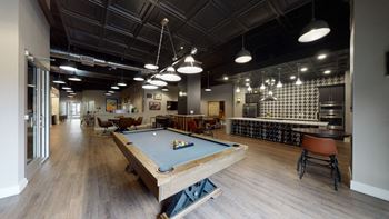 a pool table sits in the middle of a room with a bar in the background