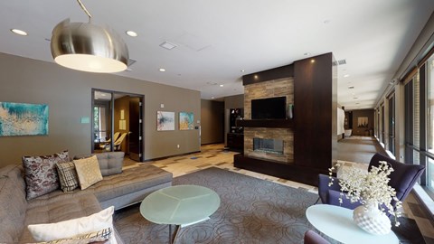 A modern living room with a grey couch and a fireplace.