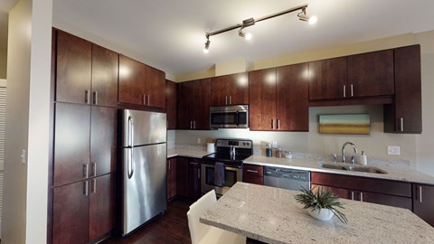 A kitchen with brown cabinets and a marble countertop.