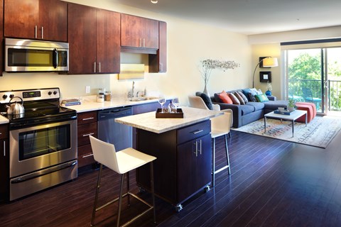 A modern kitchen with dark wood floors and stainless steel appliances.