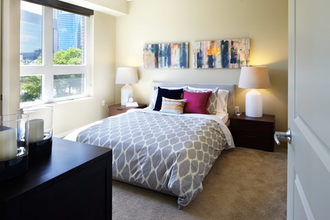 A bedroom with a patterned bedspread and two lamps on bedside tables.