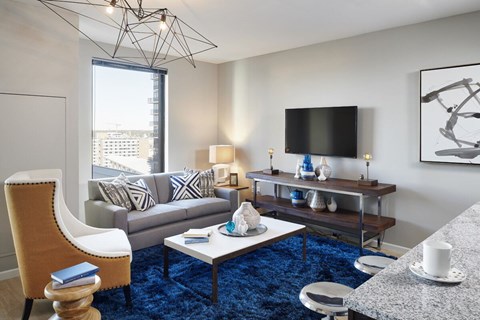 A living room with a blue carpet and a chair with a wooden seat and back.