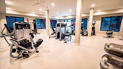 A modern fitness center here at Daymark Uptown featuring a spacious layout with light flooring, neutral walls, and large windows that bring in natural light. Strength-training machines, cardio equipment, and open floor space are arranged throughout the room, creating a clean, well-equipped environment for a variety of workouts.