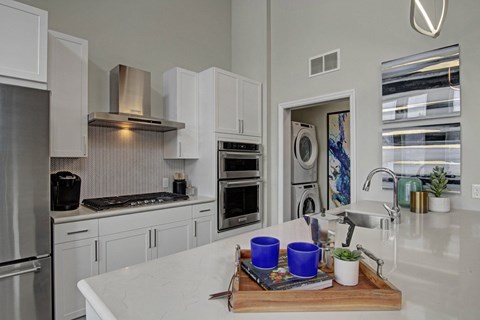 A modern kitchen with a marble countertop and stainless steel appliances.