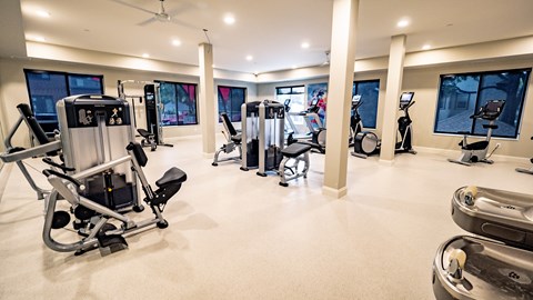 A gym with a variety of equipment including treadmills, stationary bikes, and weight machines.