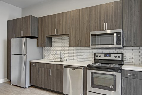 A modern kitchen with a stainless steel refrigerator, microwave, oven, and dishwasher.