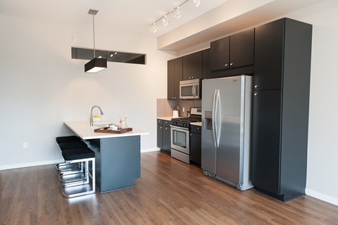 A modern kitchen with a black refrigerator and stainless steel appliances.