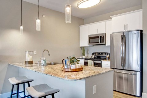 A kitchen with a granite countertop and stainless steel appliances.