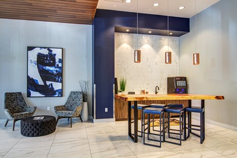 A modern bar area with a wooden counter and blue stools.