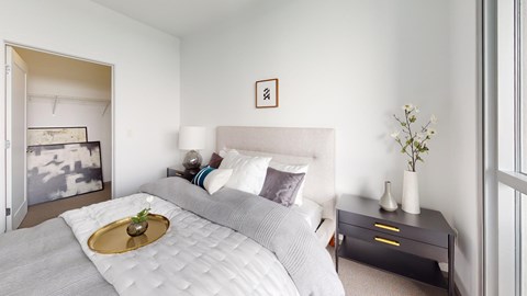 A bedroom with a large bed and a small table with a vase on it.