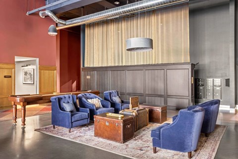 A living room with blue chairs and a rug.