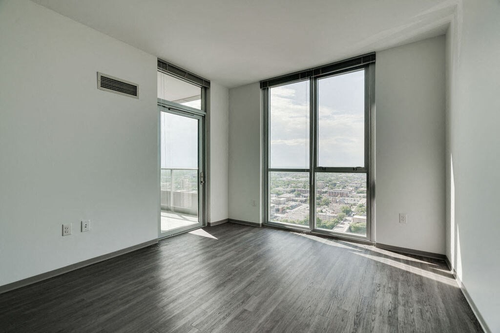 an empty room with hardwood floors and large windows with a view of the city