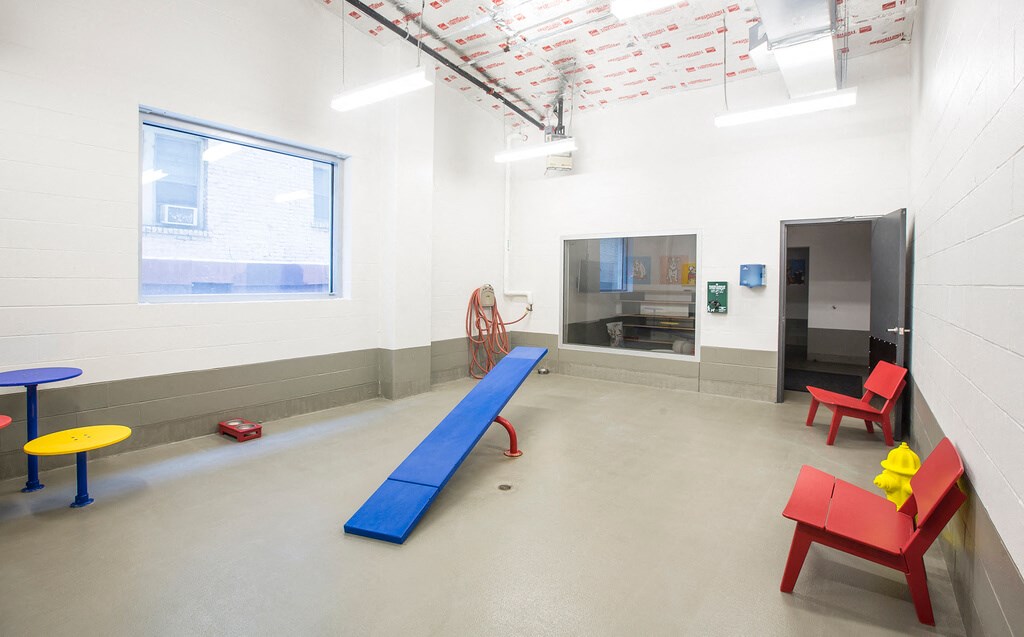 a games room with a blue play area and red and yellow chairs