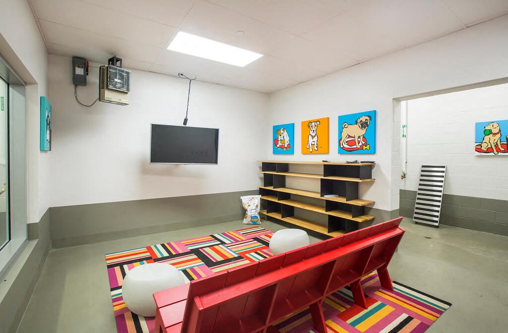 a room with a red couch and chairs and a flat screen tv on the wall