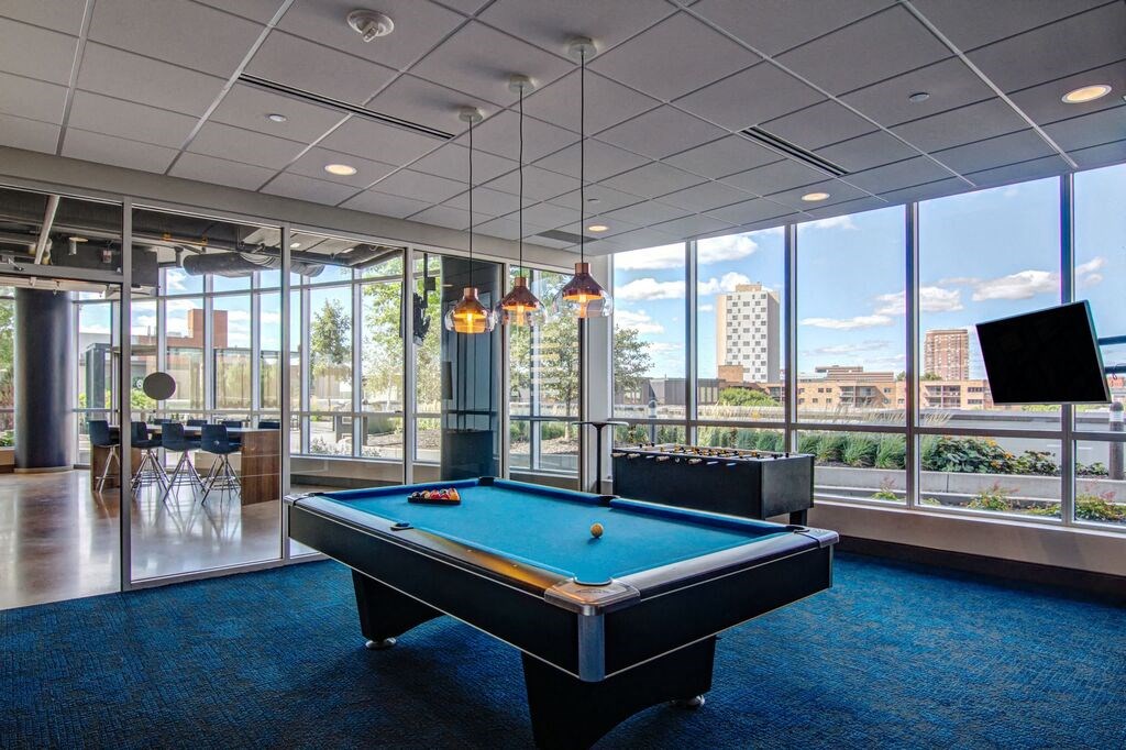 a pool table in an office space with a view of the city