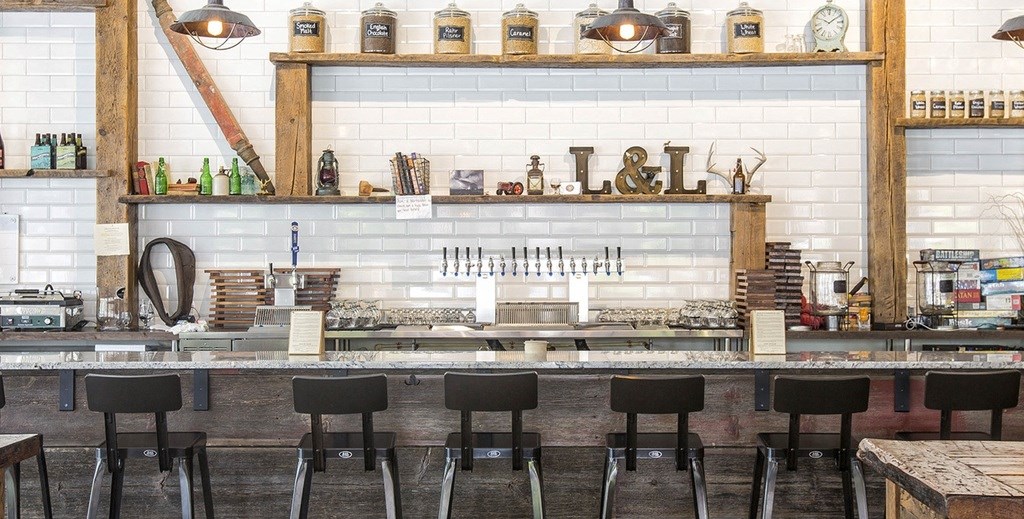 a bar with black stools and a white brick wall