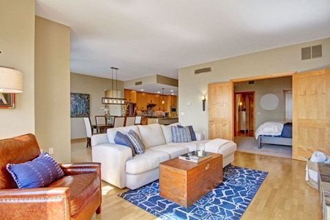 A living room with a brown leather couch and a white couch with blue pillows.