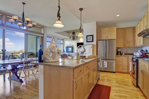 A kitchen with wooden cabinets and a marble island.