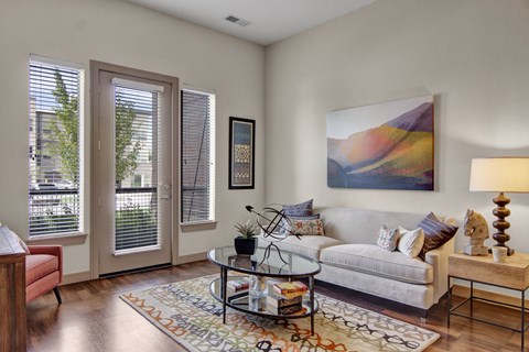 A living room with a couch, a coffee table, and a painting on the wall.