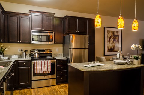 A kitchen with dark brown cabinets and a stainless steel refrigerator.