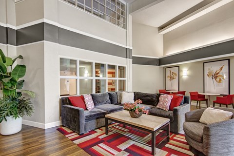 A living room with a grey couch and a red pillow.