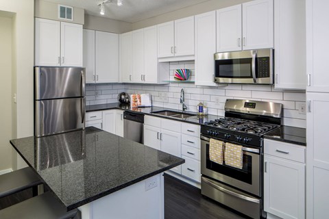 A kitchen with white cabinets and a black countertop.