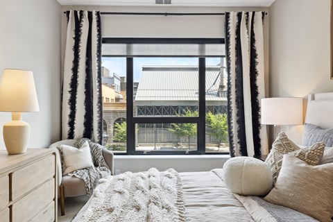 A bedroom with a large bed and a view of the city through the window.