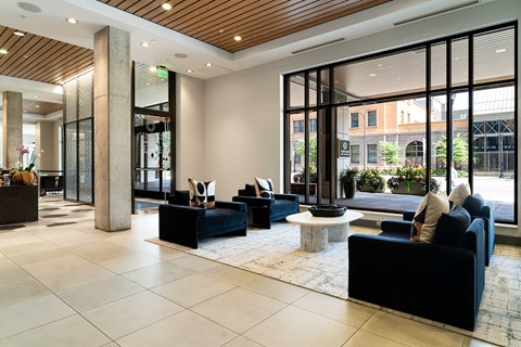 A black couch sits in a spacious lobby with a large window.