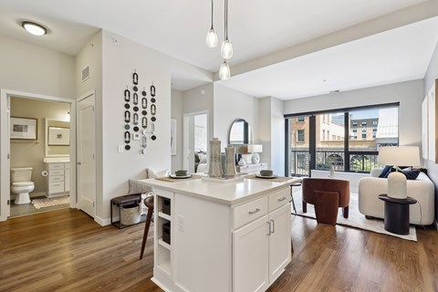 A modern kitchen with white cabinets and a wooden floor.