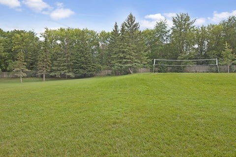 A soccer goal is in the middle of a grassy field.