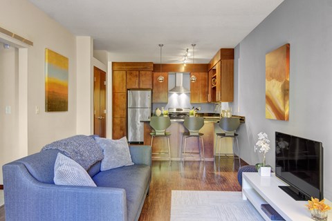 A blue couch with pillows sits in a living room with a bar and a television.