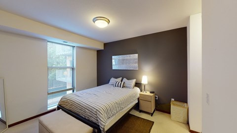 A bedroom with a bed, nightstand, and window.