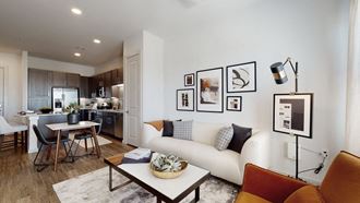 a living area with a couch coffee table and a table in front of a kitchen with a - Photo Gallery