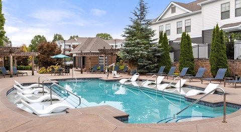 A pool with a slide and chairs around it.