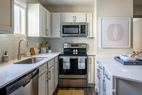 A modern kitchen with a stove top oven and a microwave above it.