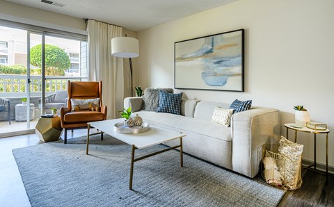 A living room with a white couch, a brown chair, and a grey rug.