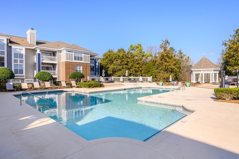 A large swimming pool in front of a building with a gazebo in the background.