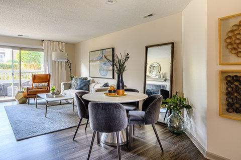 A modern dining room with a round table and grey chairs.