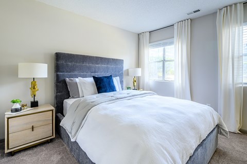A bedroom with a large bed and a nightstand with a lamp.