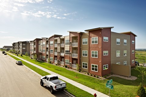 A row of apartment buildings with a white truck parked in front of the first one.