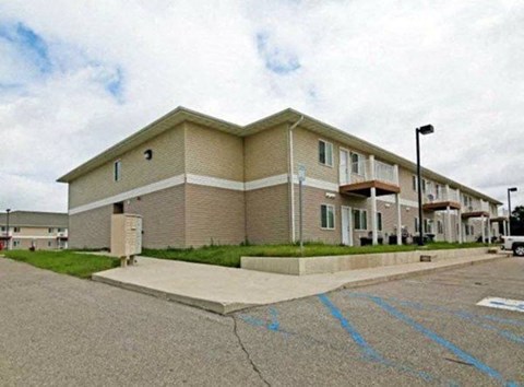 Apartment building with a parking lot in front.