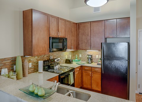 A kitchen with wooden cabinets and a black refrigerator.