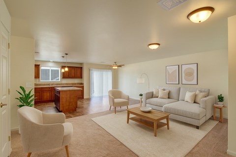 A living room with a white couch, a wooden coffee table, and a white chair.