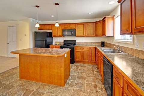 A kitchen with wooden cabinets and a black refrigerator.