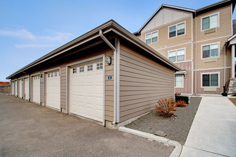 A building with a brown siding and white garage doors.