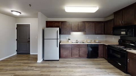 A kitchen with wooden floors and brown cabinets.
