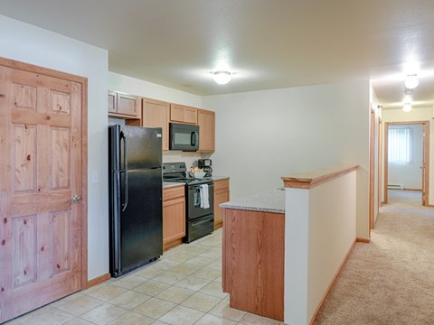 A kitchen with a black refrigerator and wooden cabinets.